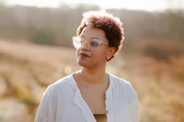 Gemma Cairney wearing a pink hat that says 'you are beautiful' she has her hands in the peace sign and is wearing a blue jacket and a leopard print top.