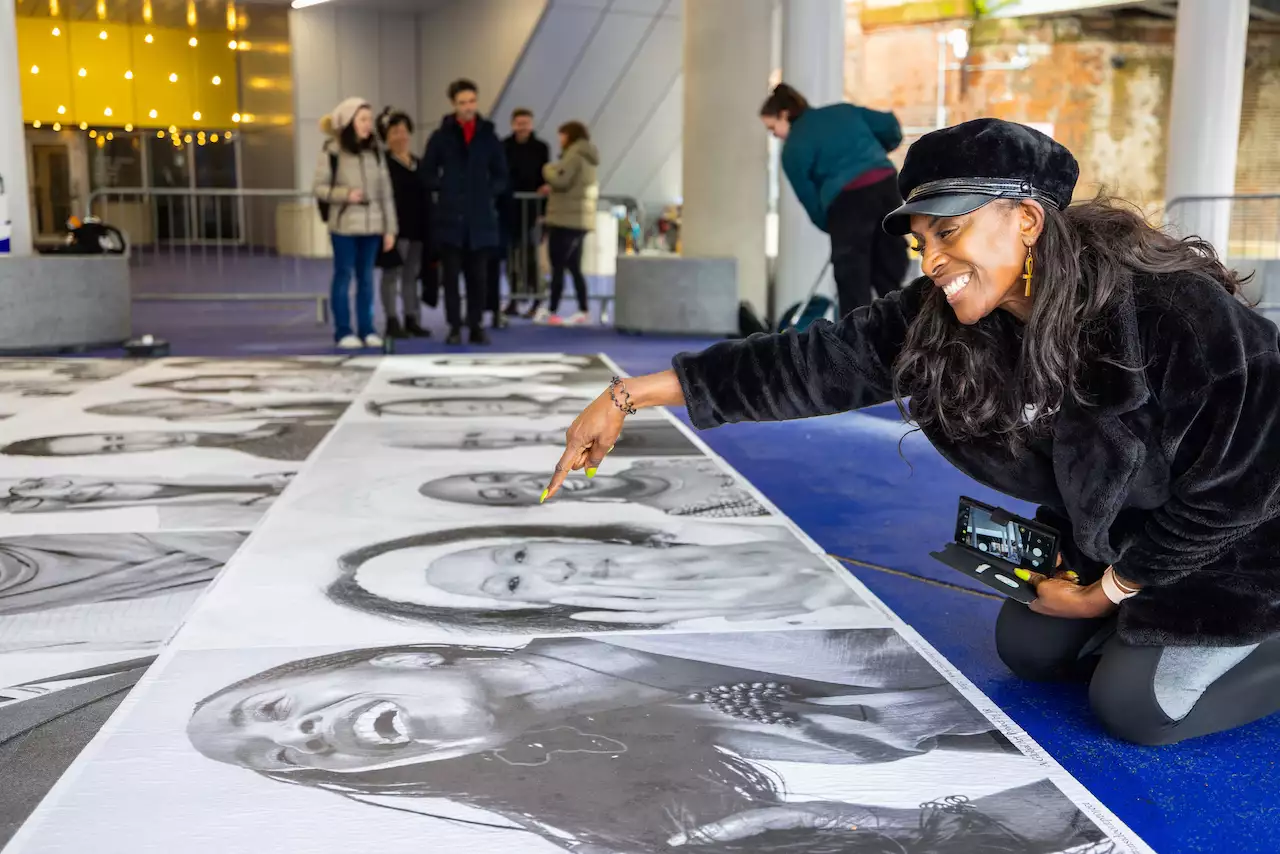 Someone pointing at a black and white portrait of themselves and smiling