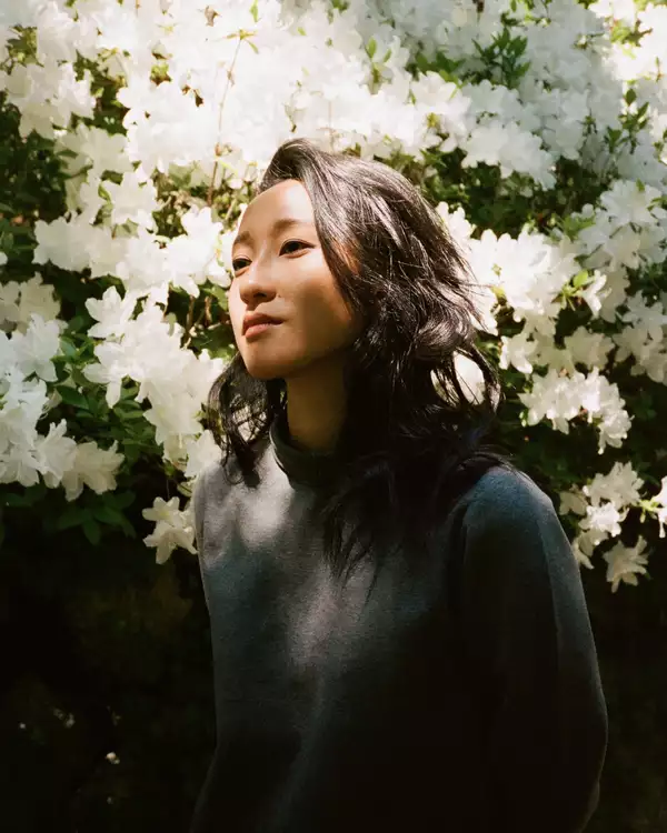 Headshot of Jessica Hung Han Yun stood in front of a bush of white flowers