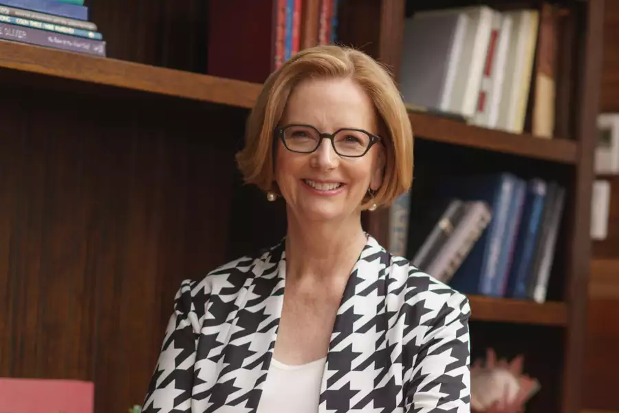 Julia Gillard smiling in front of a bookshelf