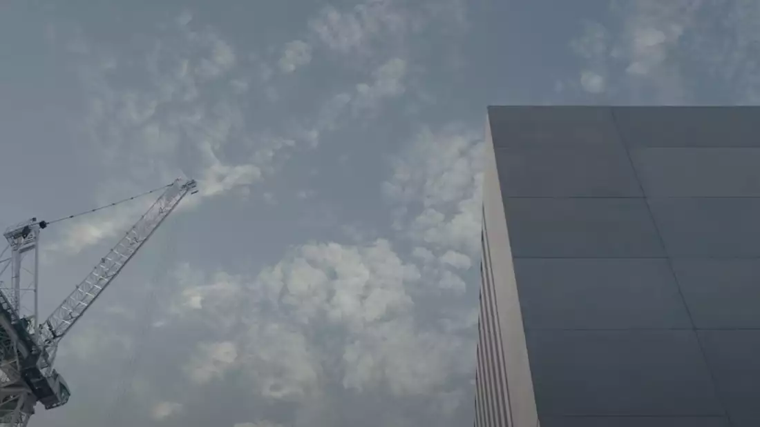 A close up of Aviva Studios architecture and a crane against a blue sky