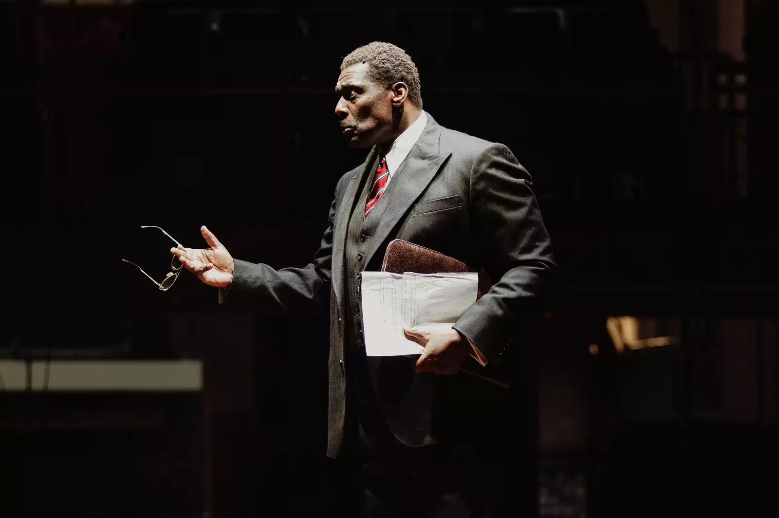 Photo of a man in a suit holding a briefcase pointing at something out of frame