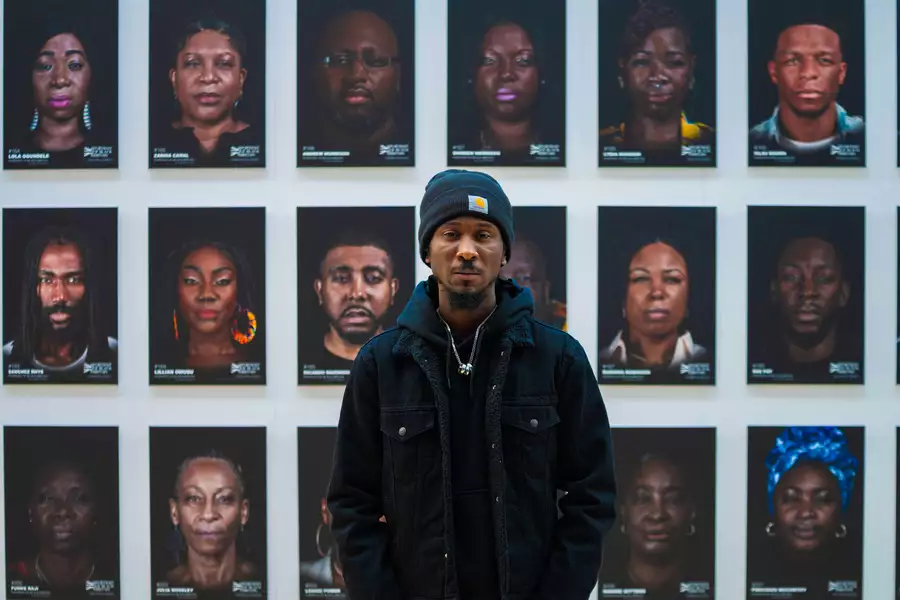 Cephas Williams stood in front of a wall of his portraits