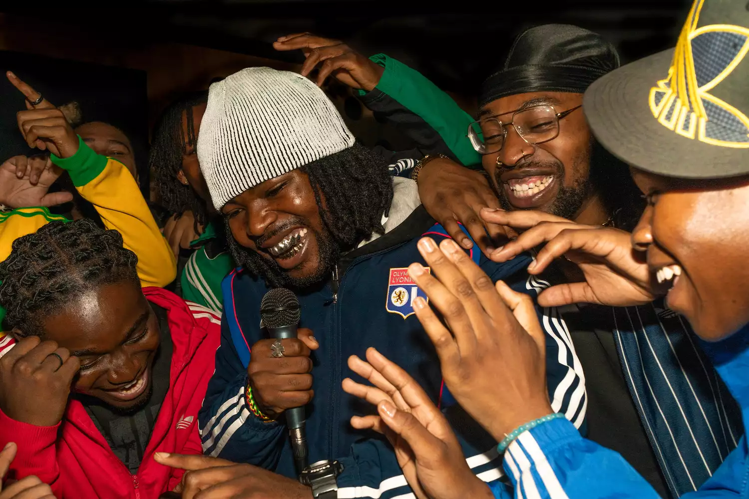 A group of people smiling and crowding around a singer who is performing in the crowd