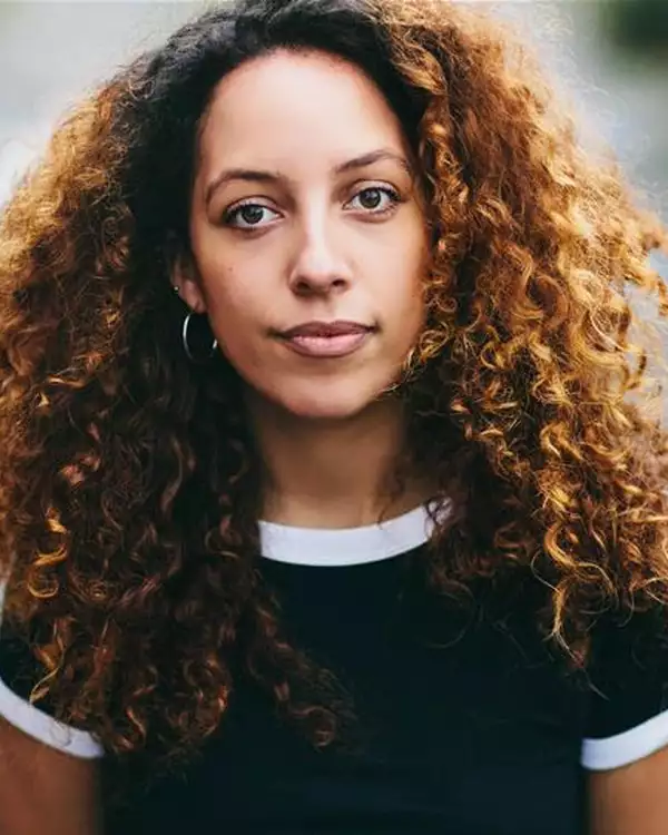 Headshot of Stefanie Reynolds wearing hoop earrings and a black top