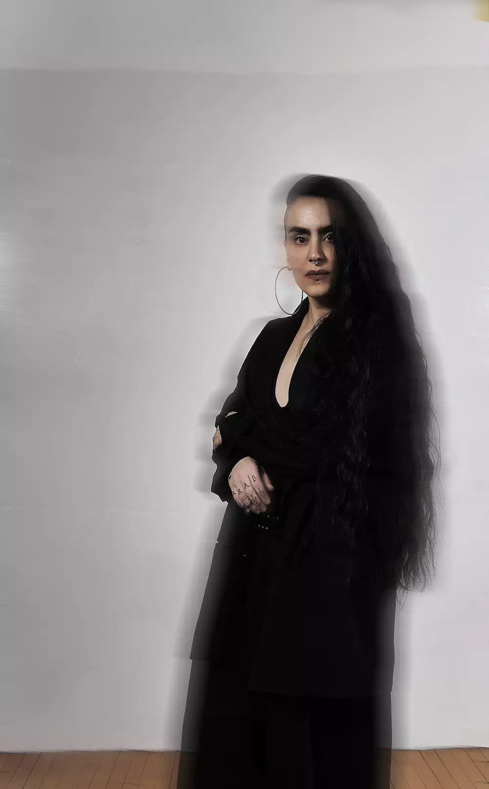 Slightly blurred portrait photo of Sonya Tayeh wearing all black on a white background