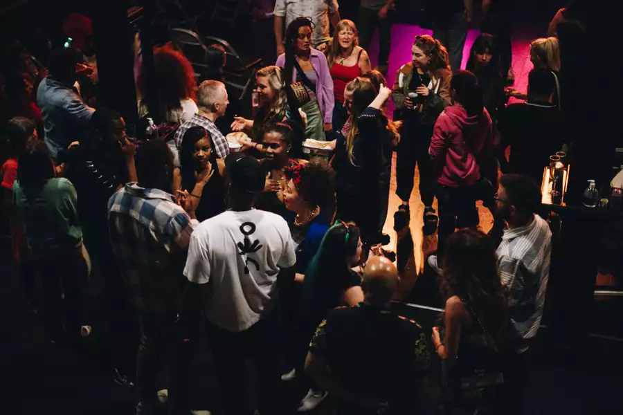 Groups of people talk and mingle in a relaxed atmosphere at an indoor venue with soft lighting.