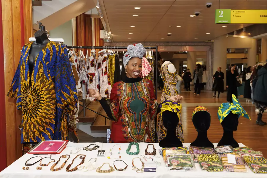 A marketplace seller smiling behind their stall of colourful accessories