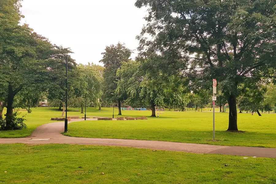A path in Ordsall Park, Salford surrounded by trees and green grass