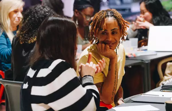 Two people sat at a table in discussion, with a piece of paper in front of them
