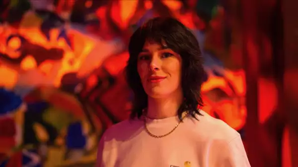 Laura Jackson wearing a white carhartt jumper with red lighting in the background