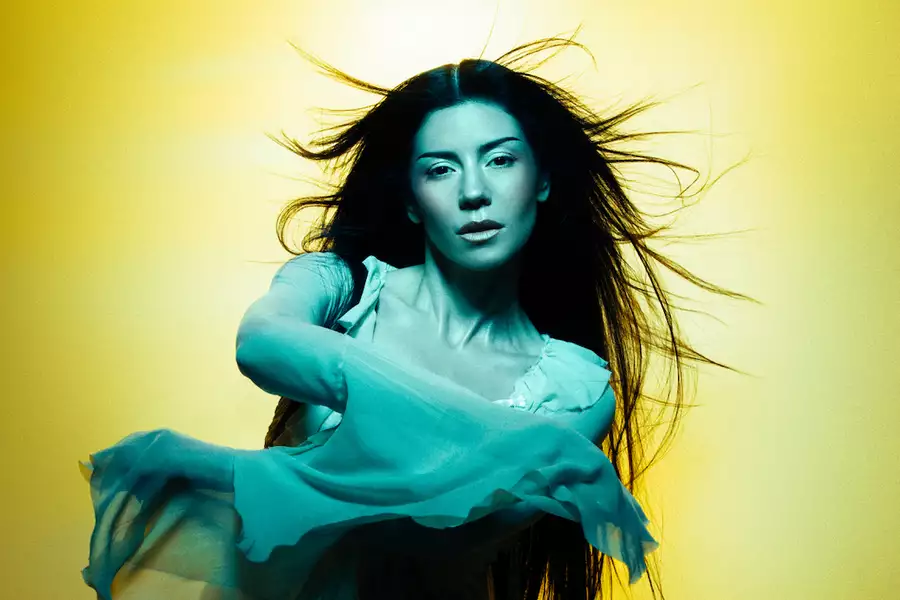 MARINA with long flowing hair poses against a yellow background