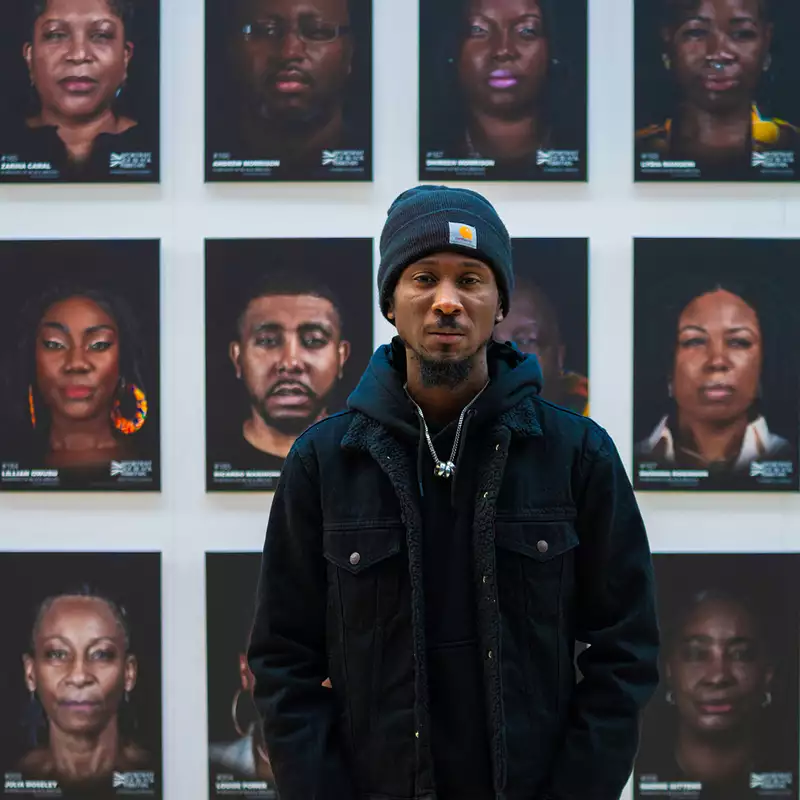 Cephas Williams stood in front of a wall of portraits