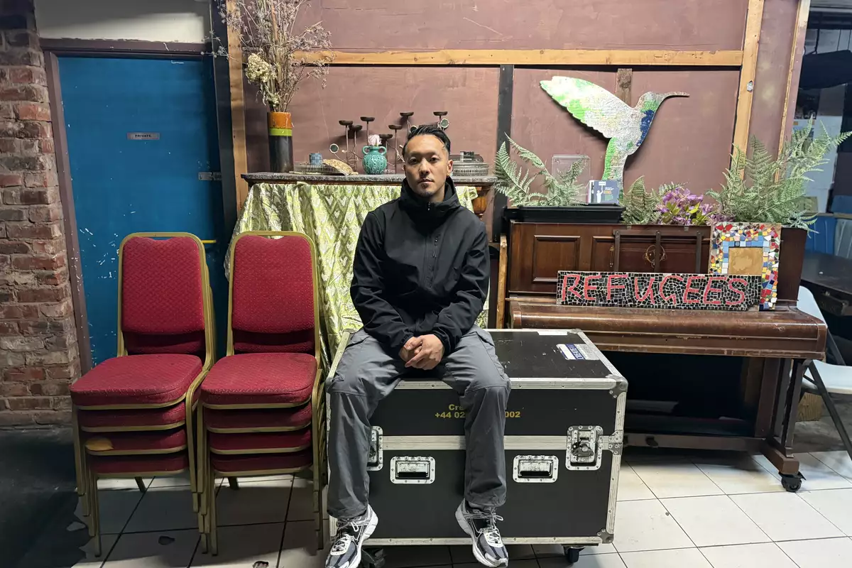 Anton Phung backstage surrounded by stacked chairs, a piano and kit boxes