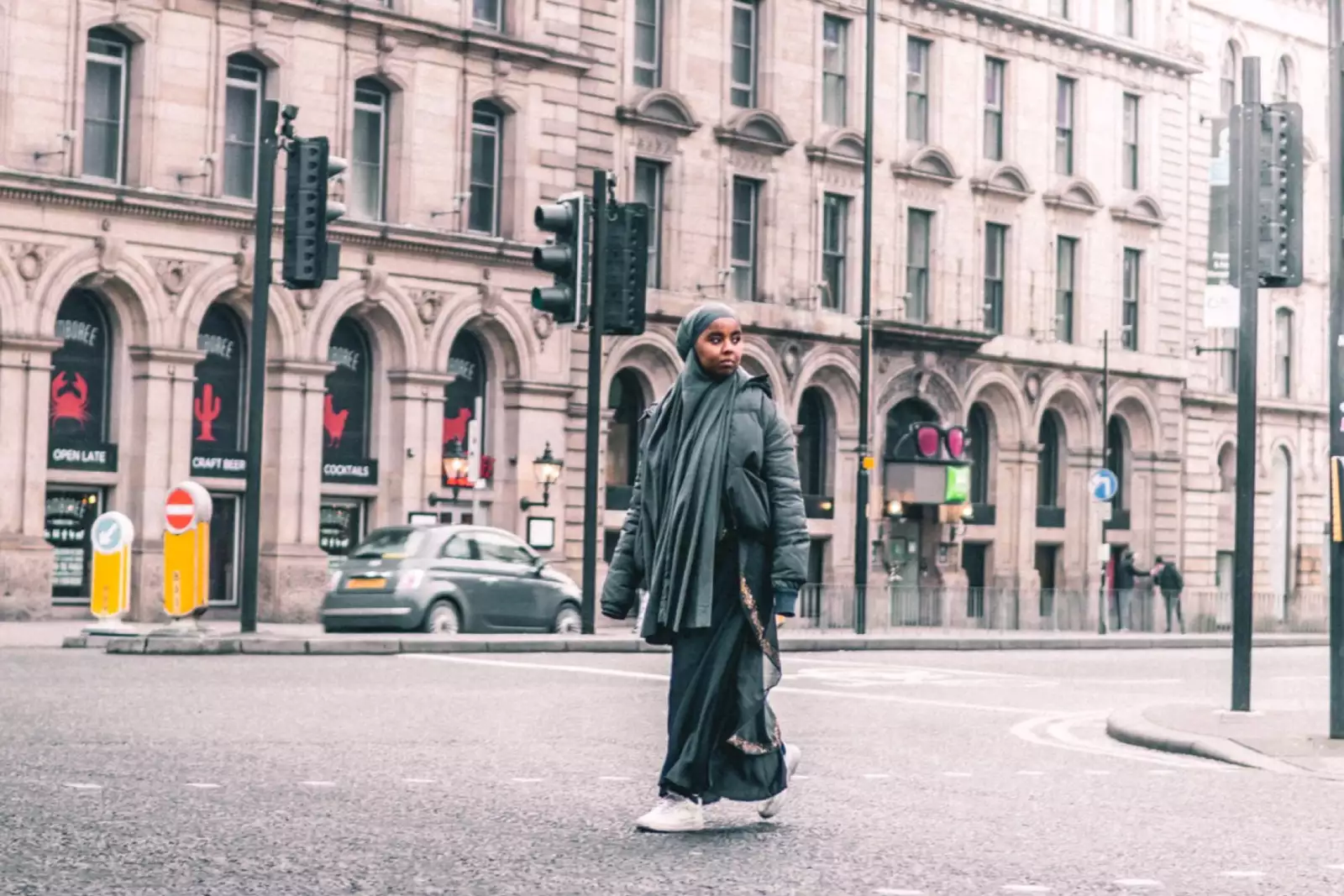 Ebyan is walking down Portland Street in Manchester city centre. She is looking at something in the distance.