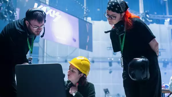 Three people working behind the scenes in the Warehouse. One is wearing a yellow hardhat.