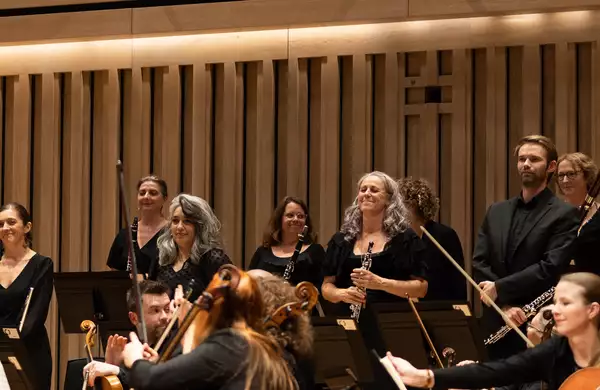 The woodwind section of Manchester Camerata standing up on stage and smiling