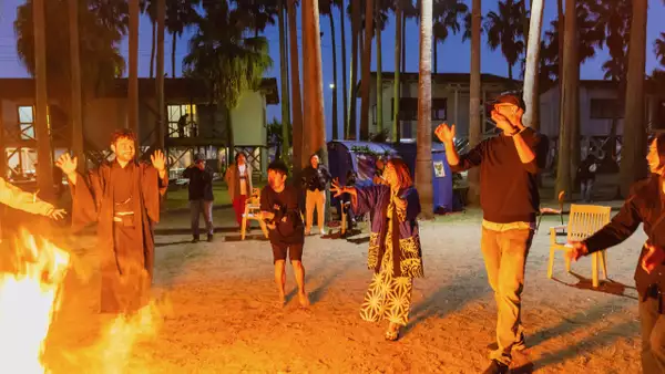 A group of people stood around a big fire outside