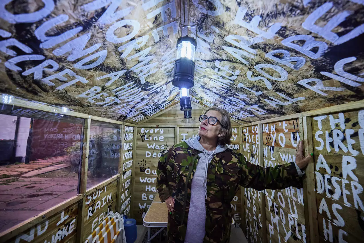Photo of a person inside a shed with writing on the walls
