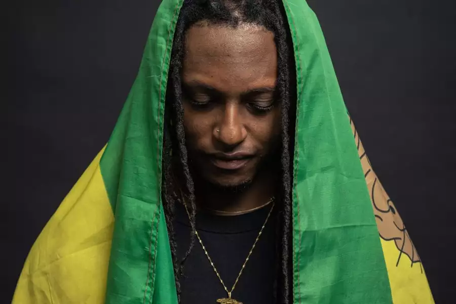Artist J Chambers looking down draped in a flag thats green and yellow