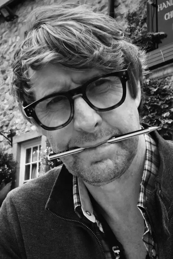 Black and white photo of Will Brenton with a pen in his mouth