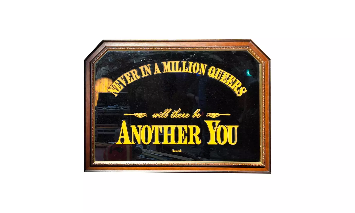 “HONESTLY MATE YOU LOOK STERLING” by Trackie McLeod, showing a framed black sign with gold lettering that reads: “NEVER IN A MILLION QUEERS will there be ANOTHER YOU.”