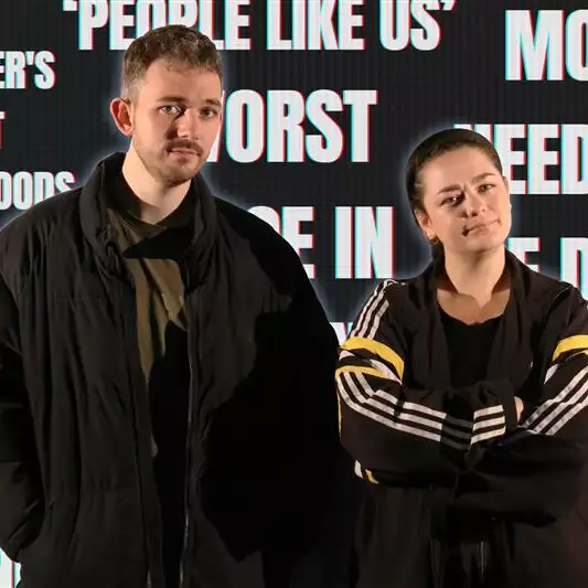 Malandra Jacks wearing black stood in front of a black wall with white text on