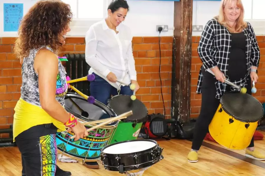 Photo of three people drumming in a circle