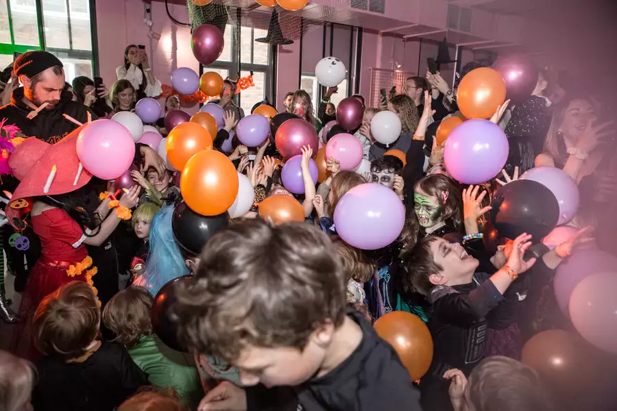 A large crowd of children dressed in Halloween outfits playing with balloons