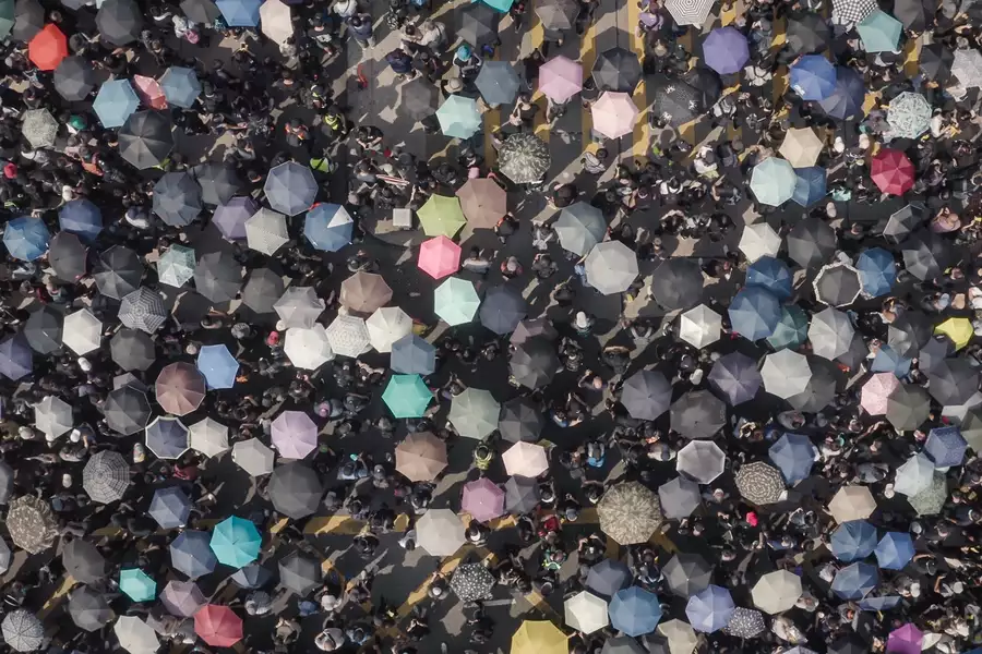 Photo taken of a crowd from above, showing multiple coloured umbrellas