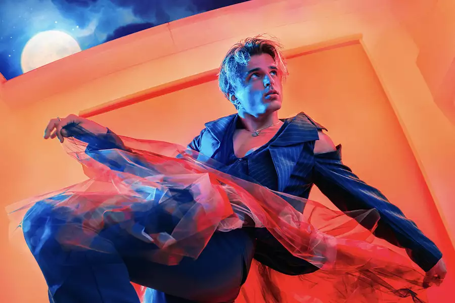 Dancer Nikita Kuzman wearing a suit with tulle in an orange room. A full moon is visible in the background