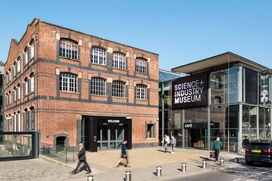 Exterior of the Science and Industry Museum on a sunny day. People are walking past the entrance.