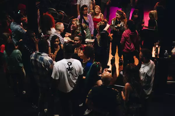 Groups of people talk and mingle in a relaxed atmosphere at an indoor venue with soft lighting.