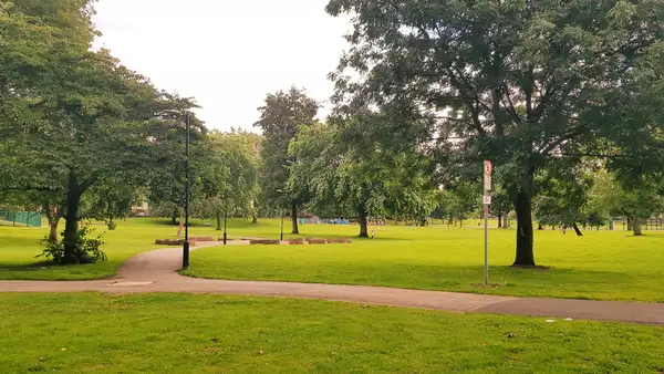 A path in Ordsall Park, Salford surrounded by trees and green grass