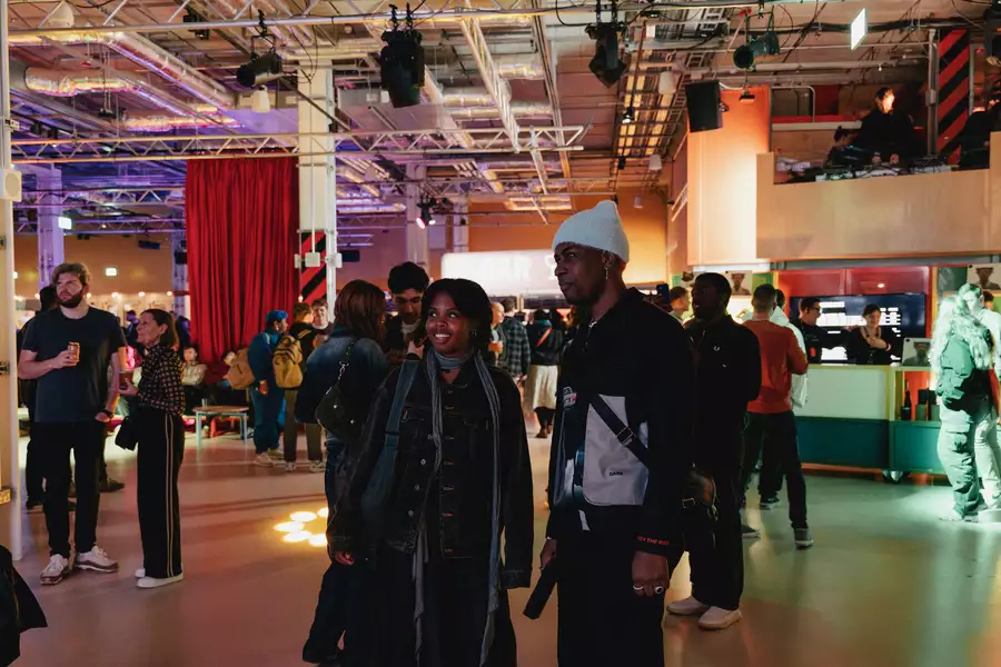 Two people stood smiling and chatting in the Social, which is busy with other people.