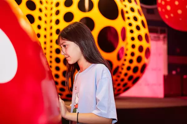 A young girl looks at a Yayoi Kusama artwork