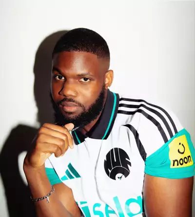 Beni De Makoso wearing a bright turquoise and white Adidas football shirt, on a white background