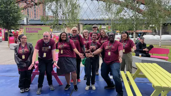 A group of volunteers smiling and laughing at Manchester International Festival 2025