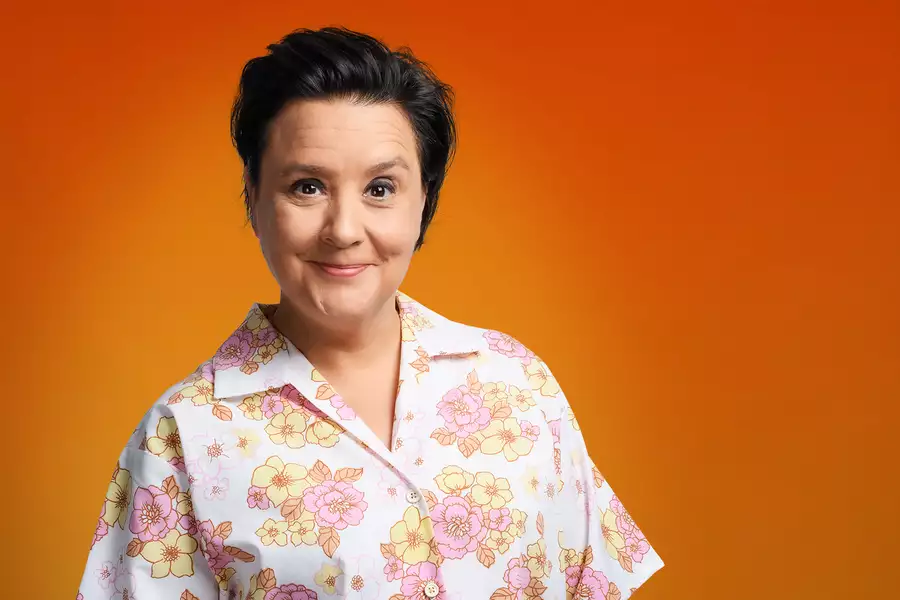 Susan Calman smiling and wearing a flowery shirt on a bright orange background