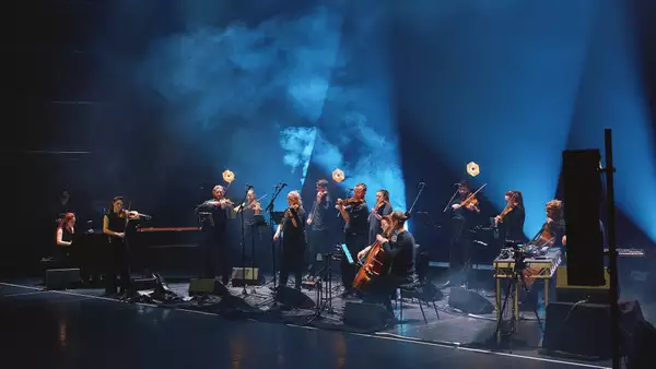 Manchester Collective performing on a stage with blue lighting