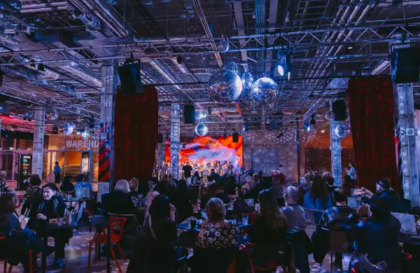 A crowd of people in the Social watching a performance on stage, with festive decorations around them