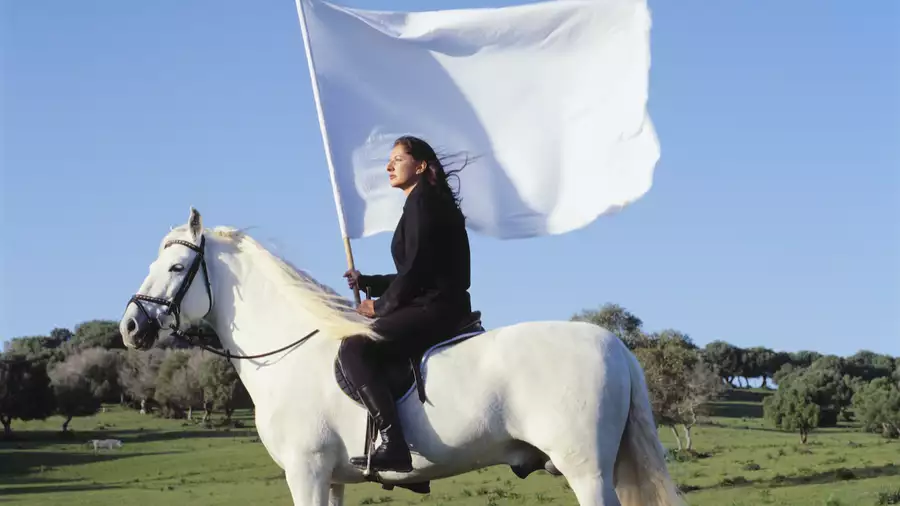 Marina Abramović on a white horse holding a white flag
