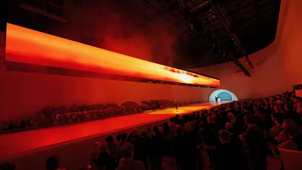 A crowd watching a dancer on stage during Free Your Mind in the Warehouse. The lighting is red.