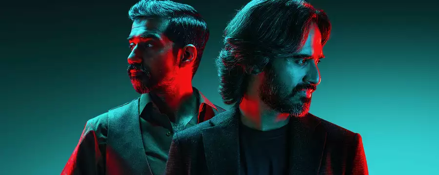 Two members of Kaavish standing back to back, looking in opposite directions, with dramatic red and blue lighting. The background is a gradient of teal.