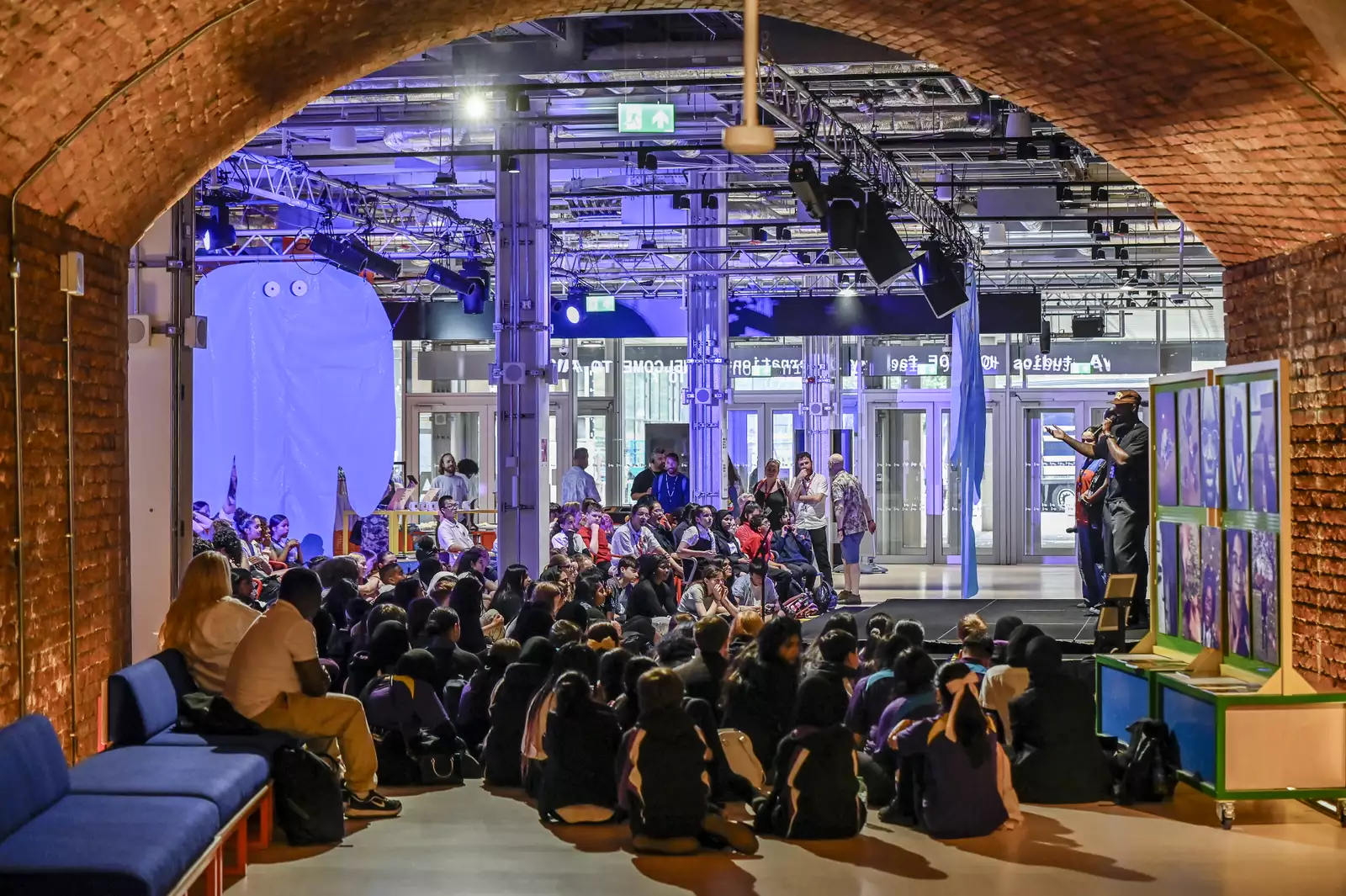 A large group of children sat on the floor of the Social, watching a performance on the stage