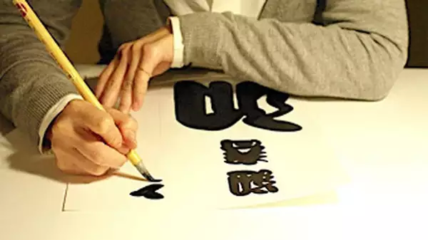 A person writing in Japanese calligraphy
