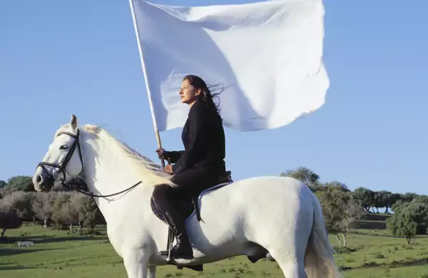 Marina Abramović on a white horse holding a white flag