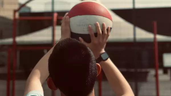 Close-up photograph of a young person throwing a ball into a hoop