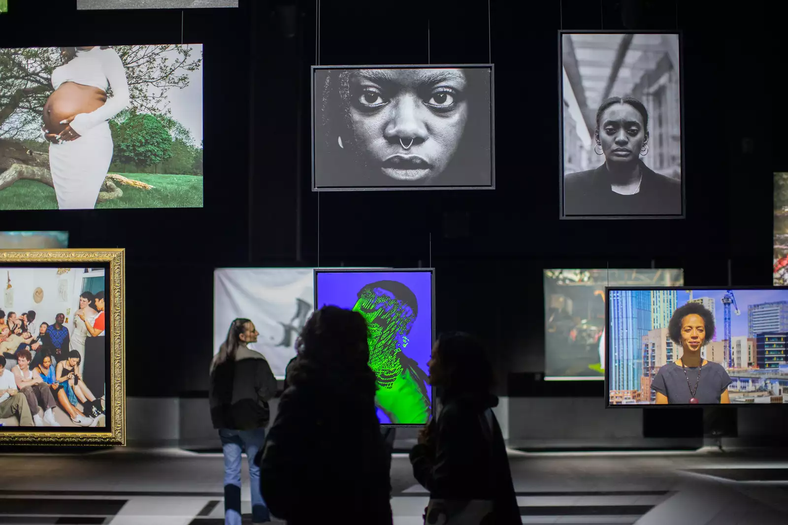 A group of people looking at the photographs displayed in the Warehouse as part of the Reframe exhibition