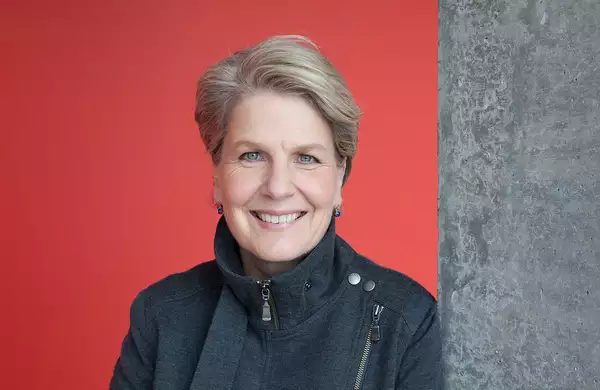 Sandi Toksvig smiling in front of a red wall